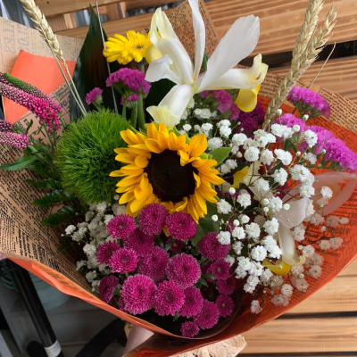 Golden Glow - Brighten someone's day with the `Golden Glow` arrangement, featuring a stunning sunflower mix with seasonal blooms. Complemented by lush green foliage, this arrangement brings a touch of nature's radiant beauty into any space.